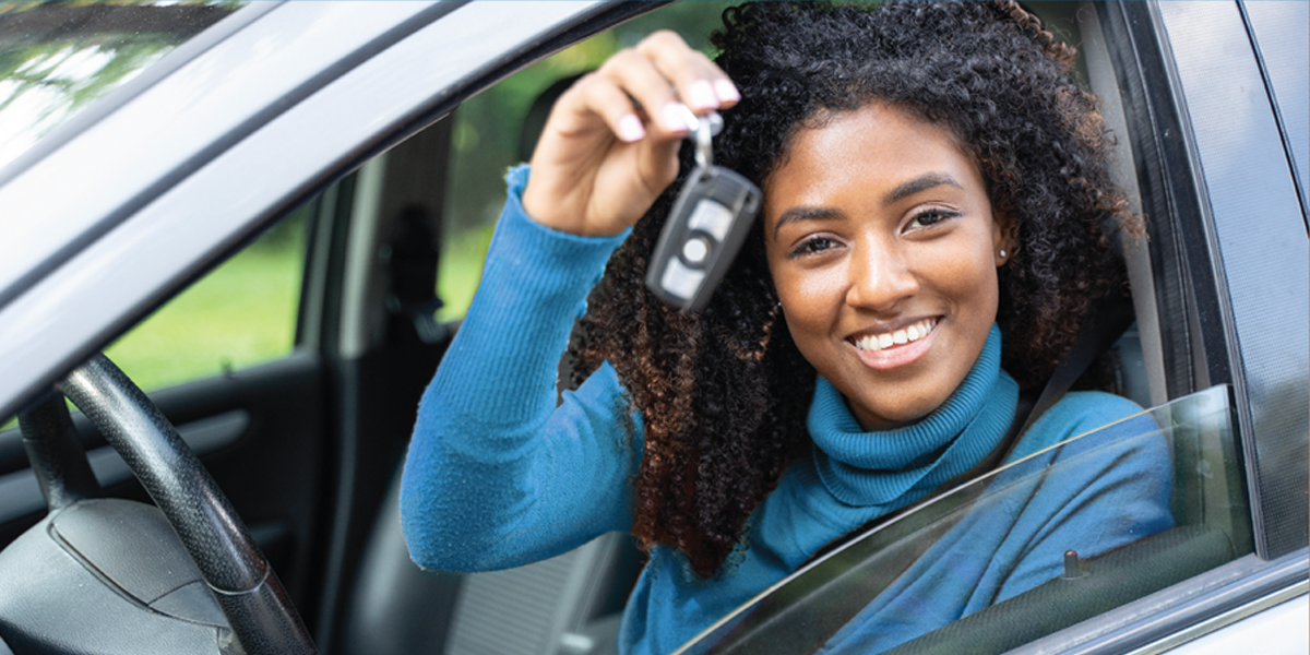 Young woman holding car keys in the driver seat