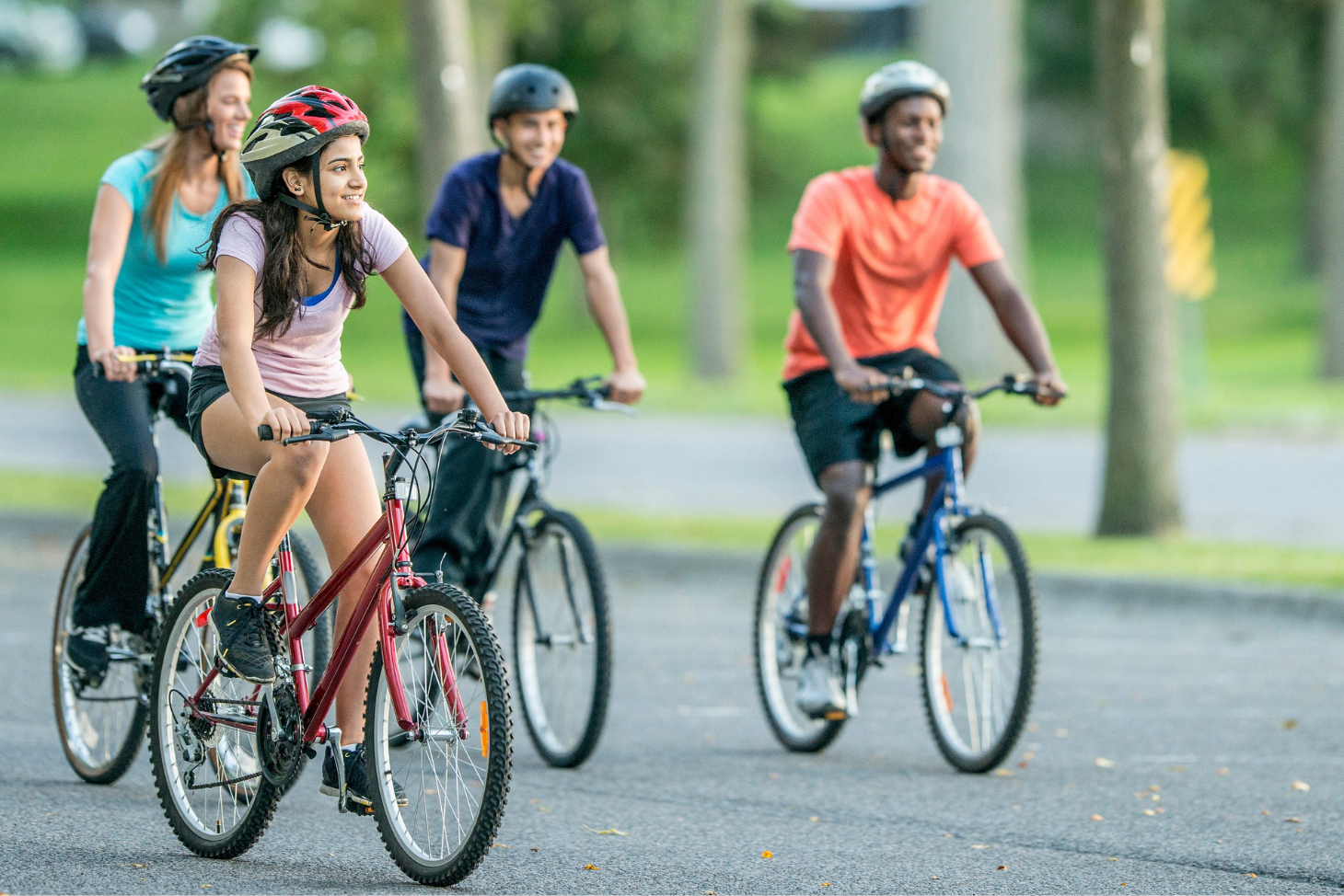 Four teens riding bikes with helmets on